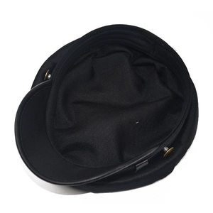 Detail of black twill flat top hat featuring a decorative gold cylindrical metal buckle