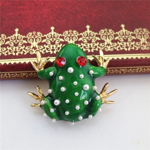 Detail of green enamel frog brooch with inlaid white pearls and red rhinestone eyes