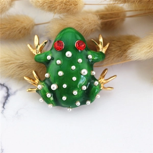 Macro shot of green enamel frog brooch with white pearls and sparkling red crystal eyes