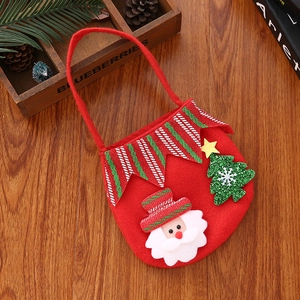 Detail of red felt Christmas gift bag featuring 3D Santa and green tree on wood floor
