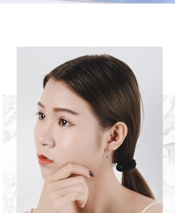Close-up of cute silver cat silhouette earrings on model with minimalist style