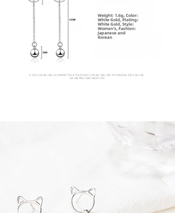 Detail view of cat bell drop earrings showing 48mm length and polished 8mm metal spheres