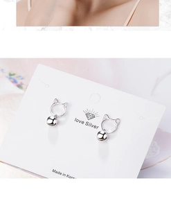 Close-up of S925 silver hollow cat head earrings with a dangling bell on white card