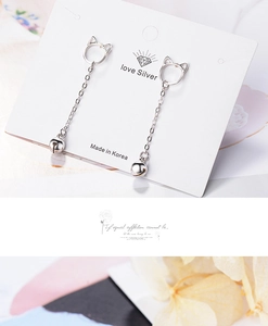 Detailed macro shot of silver cat ear studs with bell chains on a branded card
