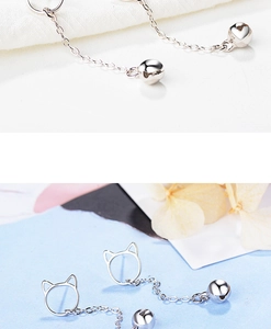 Close-up of silver cat ear stud earrings with long thin chain and ball bell detail