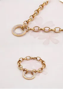 Detail of gold chain bracelet featuring a round pendant set with white crystals