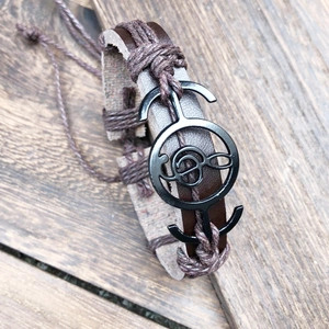 Macro shot of a braided leather musical note bracelet on a vintage wood texture