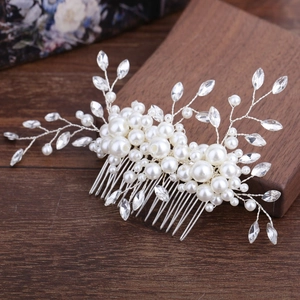 Handmade bridal hair comb with elegant white pearls and rhinestones on a wooden background