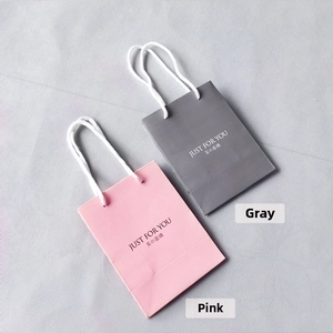 Detail of pink and grey paper gift bags with white cotton handles and Just For You text