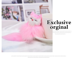 Close-up of fluffy pink and white plush fox keychain resting on a ceramic cup