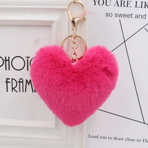 Close-up of pink heart plush keychain with golden metal clasp and fluffy texture