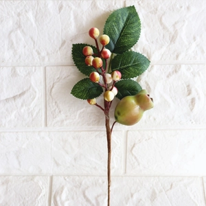 Detailed view of artificial Christmas berry branch with green leaves and realistic fruits