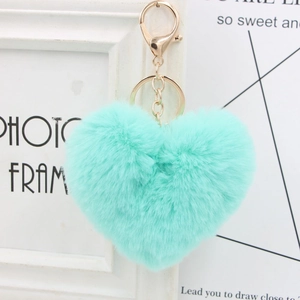 Close-up of a heart-shaped faux fur keychain in mint green with a gold metal clasp