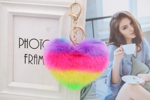Rainbow heart fluffy keychain accessory shown as a stylish bag charm in a cozy setting