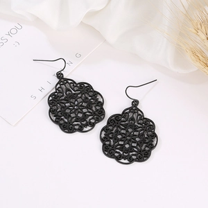 Elegant black hollow floral earrings with vintage pattern on white silk and dry grass