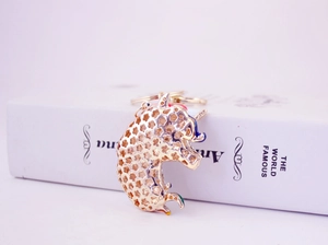 Detailed close-up of a golden unicorn keychain with colorful enamel accents on a book