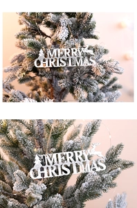Detail of silver Merry Christmas wood sign with glitter on a snowy Christmas tree