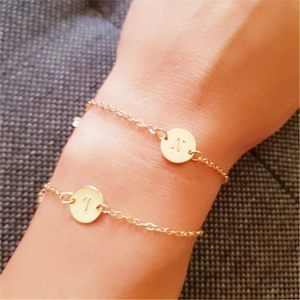 Golden double layer hollow round initial bracelets featuring letters T and N on model wrist