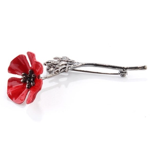Macro shot of red enamel poppy brooch with bronze leaves and pin detail