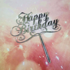 Close-up of silver reflective Happy Birthday acrylic cake topper for party desserts