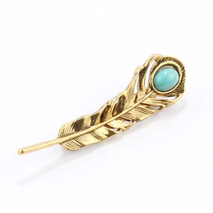 Detail of vintage gold feather brooch featuring a polished oval turquoise gemstone