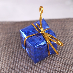 Close-up of a blue 2.5cm laser gift box ornament with a gold bow on burlap background