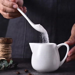 White ceramic creamer pitcher with handle and spiral texture including long spoon