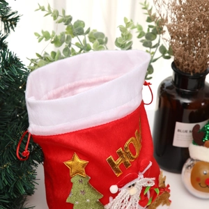 Plush red Santa Claus gift bag with festive embroidery and holiday decor background
