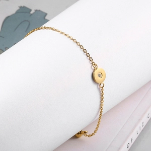Detailed shot of a gold minimalist chain bracelet with a round zircon pendant