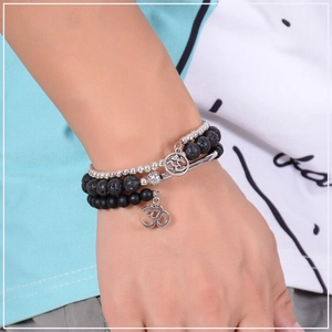 Close-up of triple-layered lava stone yoga bracelet featuring a silver Om charm