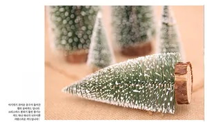 Close-up of frosted mini Christmas trees with white snow effect and natural wooden bases