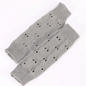 Macro detail of grey knitted arm warmers with decorative heart-shaped cutout patterns