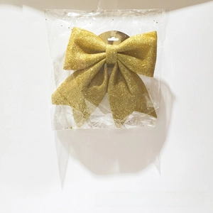 Detail of a sparkling gold glitter foam Christmas bow ornament with hanging card