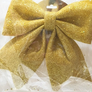 Close-up of a sparkling gold glitter Christmas bow ornament with sequins and hanging card