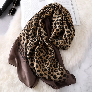 Fashionable leopard print silk scarf on plush background with sunglasses and magazine