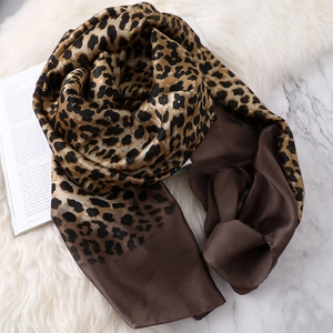 Close-up of leopard print silk scarf with gradient brown finish on marble and fur