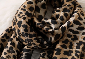 Close-up of leopard print silk scarf showing soft satin texture and delicate stitching