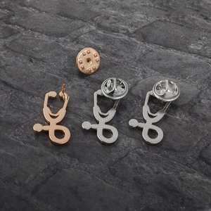 Macro shot of stethoscope alloy lapel pins in rose gold and silver finishes with back clasps