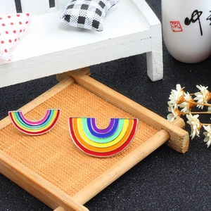 Detailed close-up of rainbow arc pins in two sizes on a textured wooden tray
