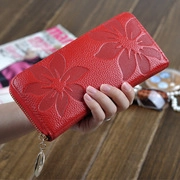 Detailed view of red floral embossed leather wallet with leaf-shaped metal zipper pull