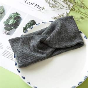 Detail view of a gray knitted cross headband styled on a decorative plate and magazine