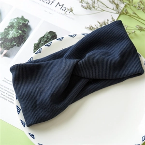 Detail of navy blue knitted twisted headband on decorative ceramic plate for styling