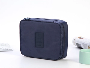 Close-up of a dark blue travel toiletry bag with leather TRAVEL logo and top handle