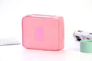 Pink rectangular travel toiletry bag with zipper and travel label on white background