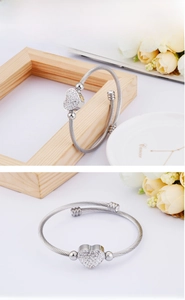 Detailed shot of silver heart charm bangle featuring a twisted rope wire texture band
