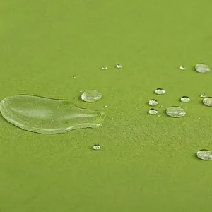 Waterproof round outdoor chair cushion in green fabric showing water resistance