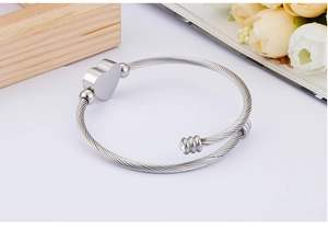 Macro view of silver cable wire bracelet featuring a heart charm and zircon detail