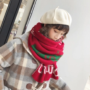 Detail of red and green knit Christmas scarf paired with a cream beret on a model