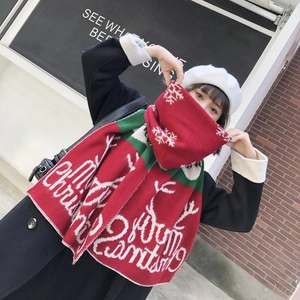 Detail of red and green knitted Christmas scarf featuring white Merry Christmas text