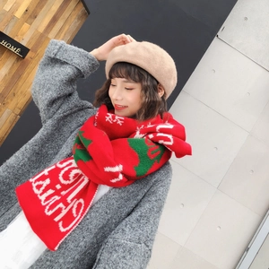 Detail of red knit scarf with white and green patterns worn by a model in a winter coat